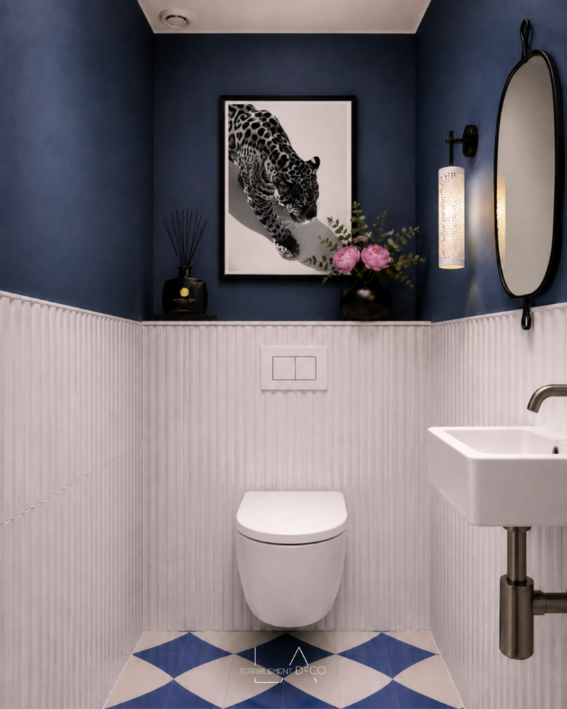 Toilettes contemporaines avec soubassement en faïence blanche, murs bleu profond, sol graphique bleu et blanc, meuble suspendu en bois et décoration contemporaine.