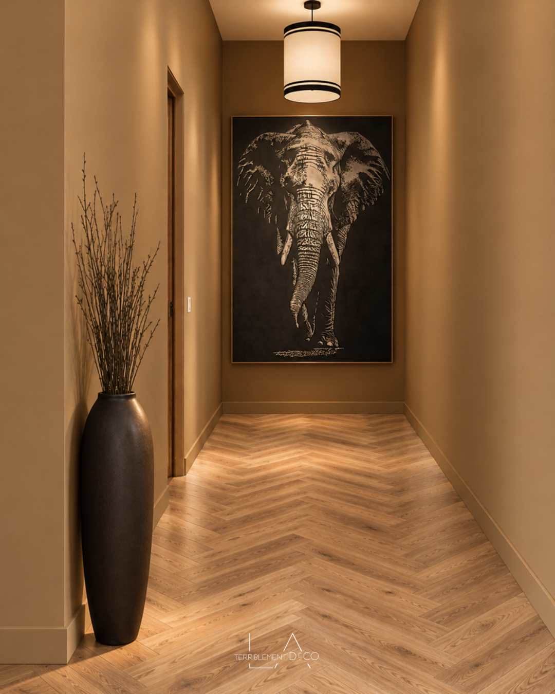 Fond du couloir, couloir aux murs tabac avec parquet en point de Hongrie, grand tableau représentant un éléphant et vase sculptural noir, un design de Laurence ARNAUD