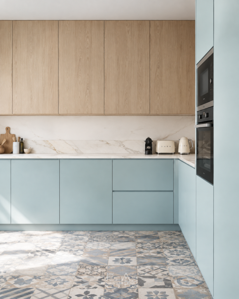 Cuisine lumineuse avec meubles bas bleu pastel, placards hauts en bois clair, crédence en marbre blanc et sol en carreaux de ciment à motifs bleus, un design de Laurence ARNAUD